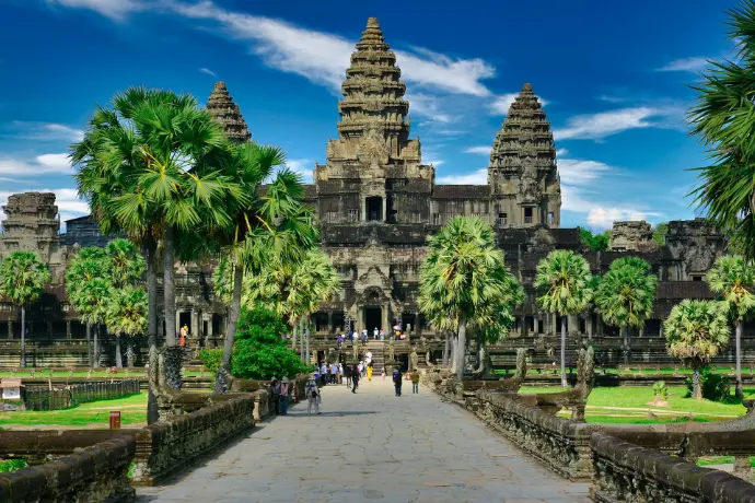 People walking along a stone path toward the Angkor Wat temple in Cambodia